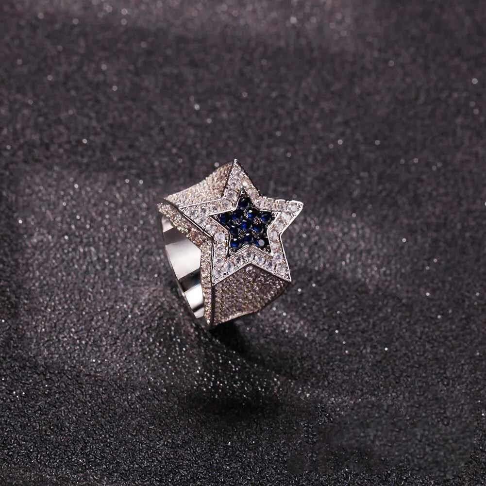 Tilted view of men’s silver‑toned iced out double pentagram star hip hop ring, heavy wide band fully encrusted with hand‑set AAA white cubic zirconia stones, center inlaid deep royal‑blue CZ star, bling statement rap jewelry for street style, nightclub outfit and holiday gift ideas for men from RDRIP JEWELRY
