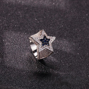 Tilted view of men’s silver‑toned iced out double pentagram star hip hop ring, heavy wide band fully encrusted with hand‑set AAA white cubic zirconia stones, center inlaid deep royal‑blue CZ star, bling statement rap jewelry for street style, nightclub outfit and holiday gift ideas for men from RDRIP JEWELRY
