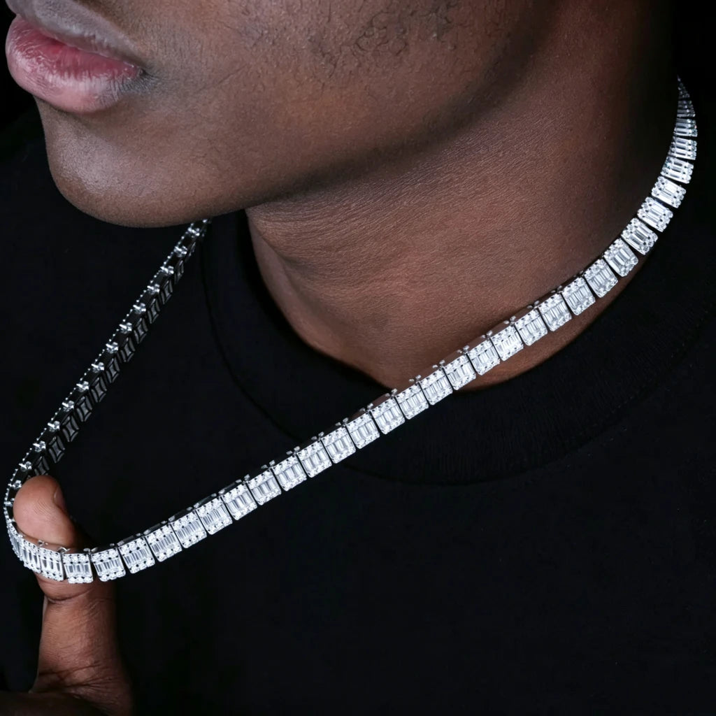 Close-up portrait shot of single layer 8MM rectangular baguette cut VVS1+ D color moissanite tennis link chain held by male model's hand against plain black background, clean smooth skin with lightened tone, solid S925 sterling silver with polished white gold plating, square link design set with center baguette moissanite surrounded by round accent stones, brilliant rainbow light refraction and icy sparkle, premium genuine moissanite with 9.25 Mohs hardness, far more shine than cubic zirconia and diamond 