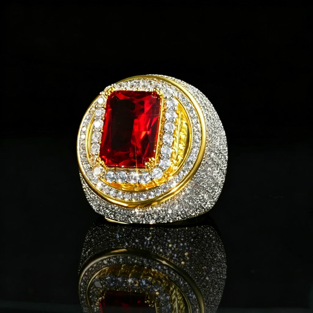 Three‑quarter angle studio product photo of two‑tone 18k gold plated men hip‑hop champion ring, large rectangular radiant‑cut red ruby center gem secured by gold prongs, striking double layered halo setting, full micro pave hand‑set cubic zirconia stones all over heavy thick wide band, brilliant icy bling and sparkling light effects, presented on glossy black mirror reflective surface, solid dark studio background, bold luxury rapper statement jewelry RDRIP JEWELRY
