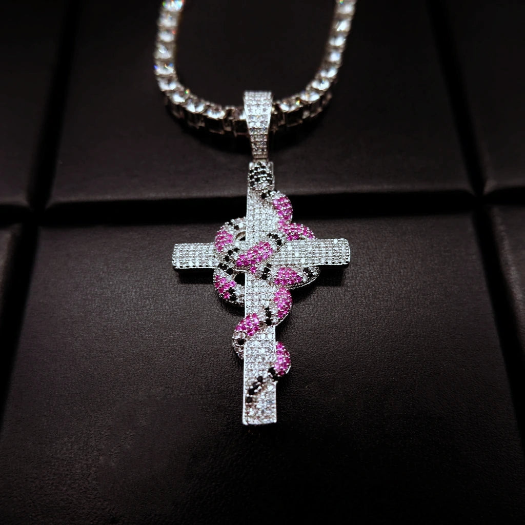 top down angle shot silver toned iced out coral snake wrapped cross pendant paired with clear stone tennis chain micro paved pink and black cubic zirconia serpent cross hip hop bling necklace for street men jewelry RDRIP JEWELRY
