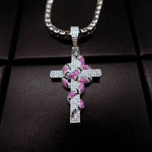 top down angle shot silver toned iced out coral snake wrapped cross pendant paired with clear stone tennis chain micro paved pink and black cubic zirconia serpent cross hip hop bling necklace for street men jewelry RDRIP JEWELRY
