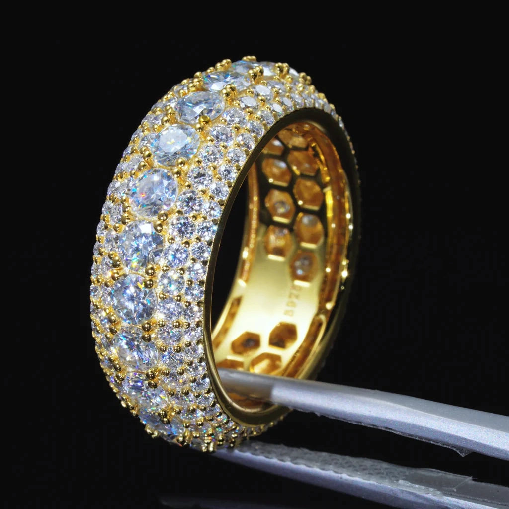 Angled studio shot of men’s 9mm wide multi‑layer full pave iced‑out moissanite eternity band RDRIP JEWELRY SINCE 2016, ring held by metal jewelry tweezers against pure black background. 18K gold plated solid 925 sterling silver band with inner honeycomb hollow construction, hand‑set 4mm D‑Color VVS1 hearts and arrows round moissanite stones, gold bead prong setting, brilliant sparkle, premium hip‑hop bling men’s statement jewelry

