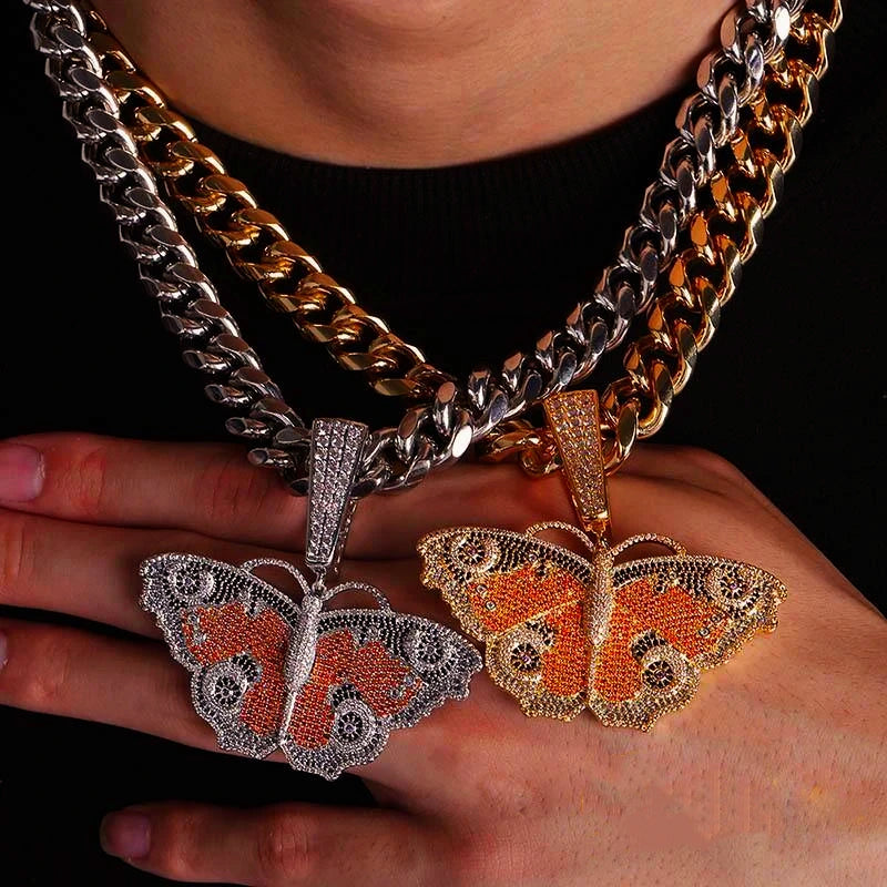 Two Iced Out Vintage Butterfly Pendants silver tone and gold tone version comparison shot held in hand, multi‑colored micro pave cubic zirconia hip hop charms matched with heavy iced cuban link chains, men street rapper fashion jewelry showing two color options RDRIP JEWELRY SINCE 2016

