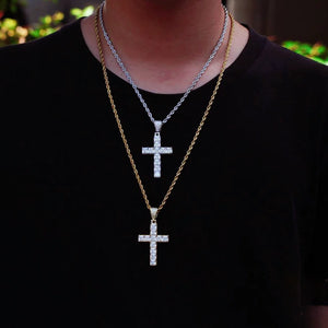 Men outdoor lifestyle shot with two layered baguette iced cross pendants, white gold silver cross on rope chain stacked with gold tone cross necklace, dual tone hip hop religious street jewelry worn on black t‑shirt RDRIP JEWELRY
