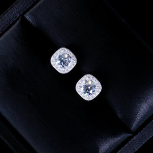 VVS1 Moissanite 7MM Cushion Halo Stud Earrings, 925 sterling silver white gold plated screw‑back unisex hip‑hop studs, round center VVS1 moissanite surrounded by pave cushion halo frame, vivid fire dispersion and bright starburst sparkles, angled close‑up shot of earrings resting inside luxury black silk‑lined gift box, premium gift ready jewelry presentation, RDRIP JEWELRY
