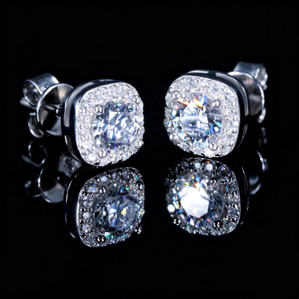 VVS1 Moissanite 7MM Cushion Halo Stud Earrings, 925 sterling silver white gold plated screw-back unisex hip hop studs, side angle view of cushion halo frame with round center VVS1 moissanite, pave set surrounding stones, visible earring post and screw-back structure, brilliant diamond-like fire, bright starburst highlights and long sparkles, clean product shot with mirror reflection on glossy black surface, RDRIP JEWELRY
