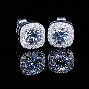 VVS1 Moissanite 7MM Cushion Halo Stud Earrings, 925 sterling silver white gold plated screw-back earrings, side view of cushion halo frame with round center VVS1 moissanite, pave set surrounding stones, brilliant diamond-like fire, bright starburst highlights and long sparkles, unisex iced-out hip hop bling studs, clean product shot with mirror reflection on glossy black surface, RDRIP JEWELRY
